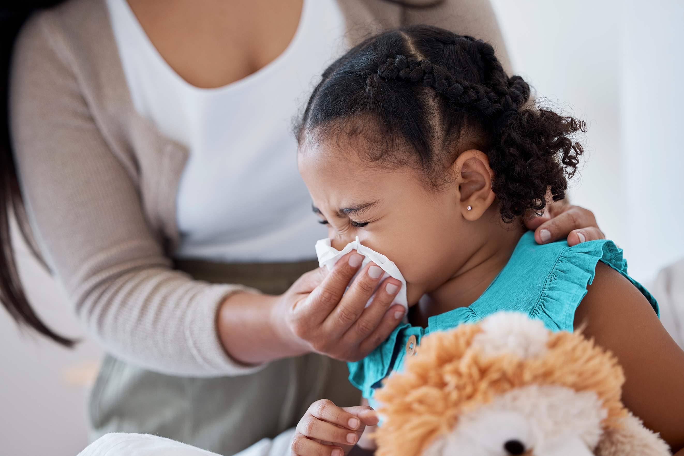 Child Illness. A mother holds a tissue to her child's nose.